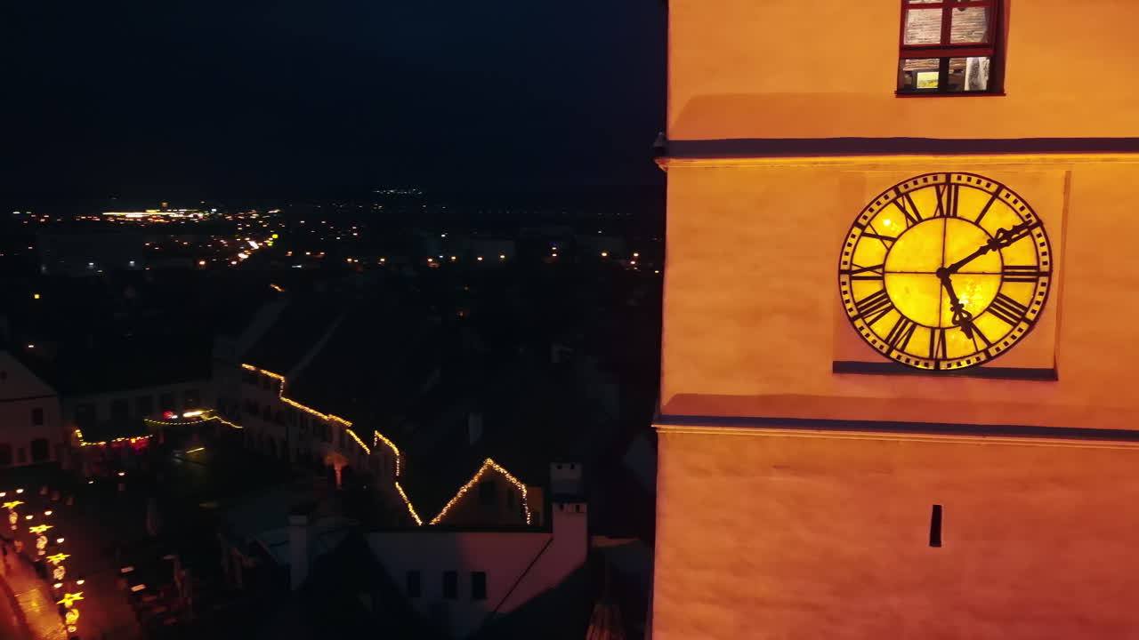 Aerial drone view of The Big Square in Sibiu at night, Romania. Old city centre decorated for Christmas. Ferris wheel, skating rink, bell tower, people
