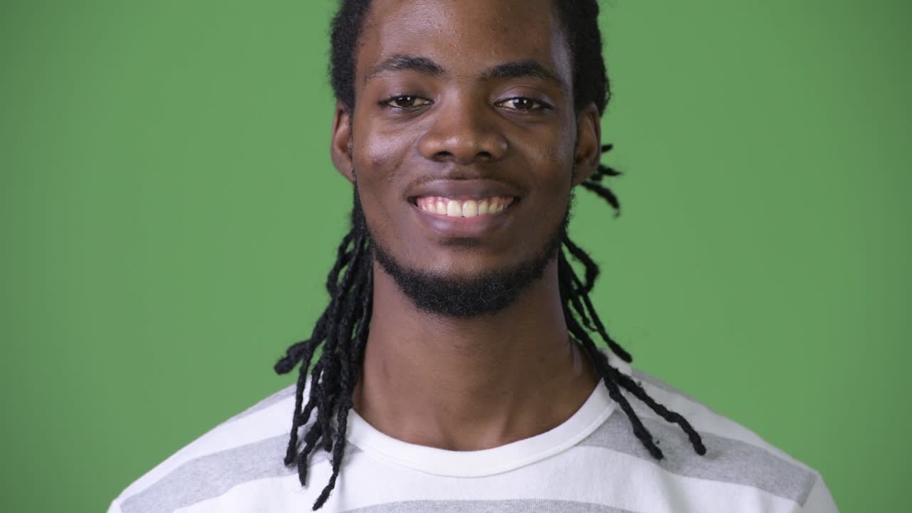 joven hombre africano guapo con dreadlocks contra un fondo verde