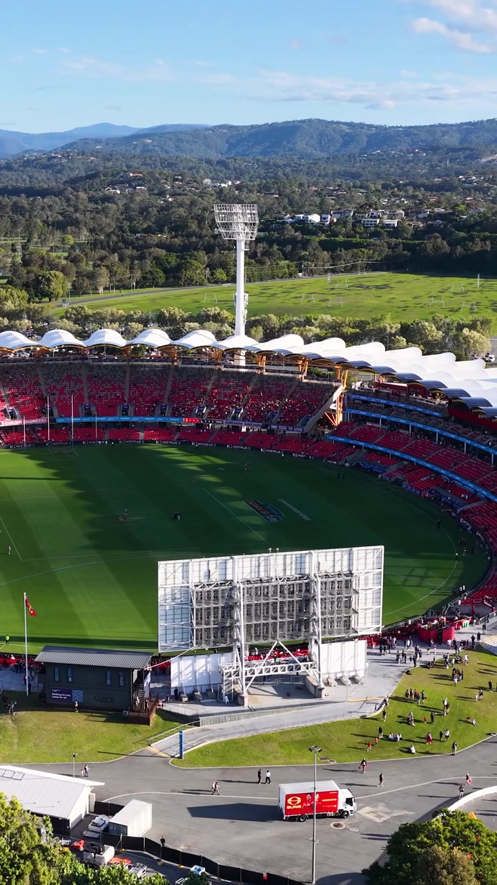 High angle aerial shot of a large sports arena under bright daylight and blue skies.