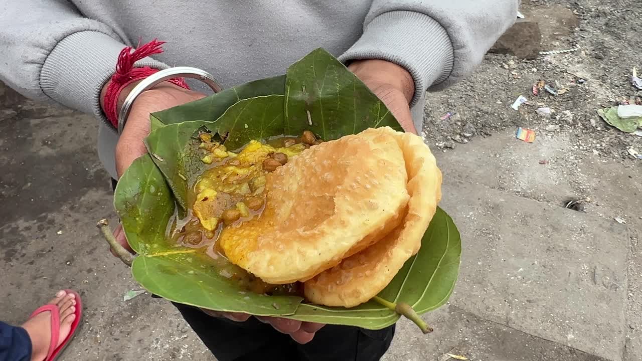 찰칸드 주 란치에서 이른 아침에 고객의 손에 사쿠아 잎으로 푸리와 사브지를 제공했습니다.