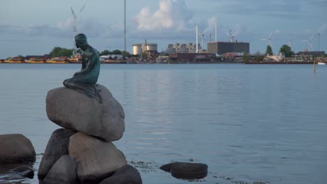 little mermaid statue against a background of harbor