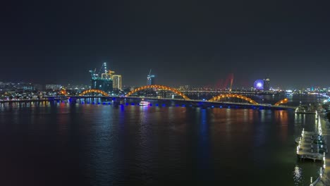 famous dragon bridge with colorful lights at night crossing river han in danang, vietnam. wide static shot