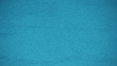 superficie de agua en la piscina con gotas de lluvia