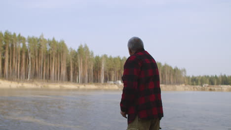 fisherman is casting a fishing rod with bait inside water of river standing on shore fishing trip in ecological place