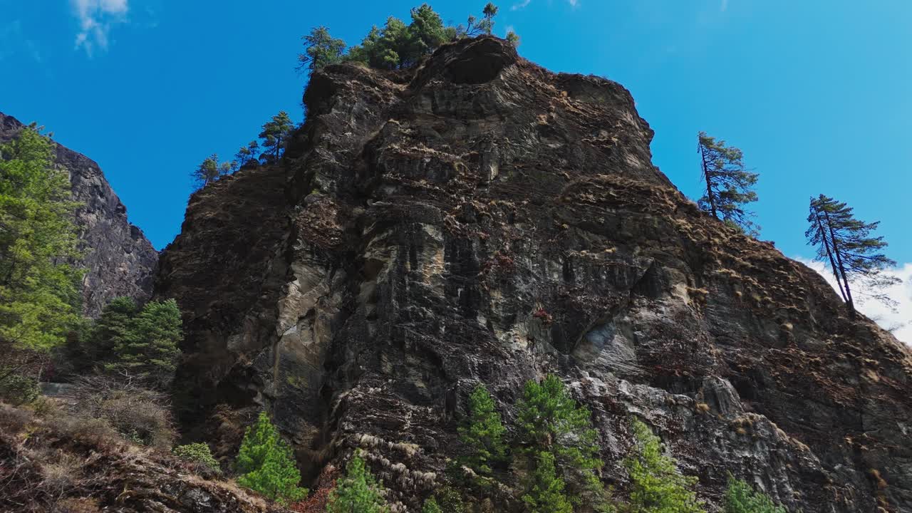 Marvel at the stunning contrast of dark rocky Himalayan mountains and vibrant green trees—raw beauty and color in perfect harmony.