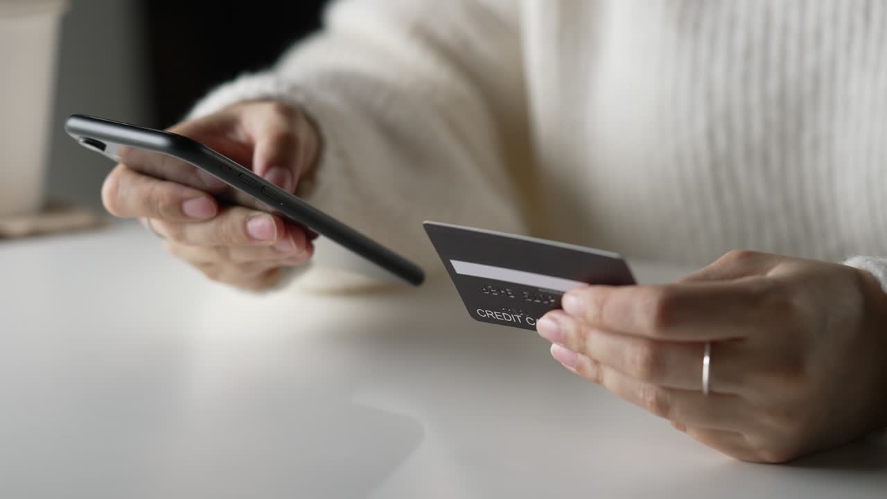Female hands holding credit card and using smartphone. Online shopping