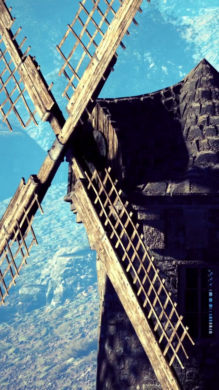Un mulino a vento si erge imponente contro il cielo blu vicino a un paesaggio rurale.