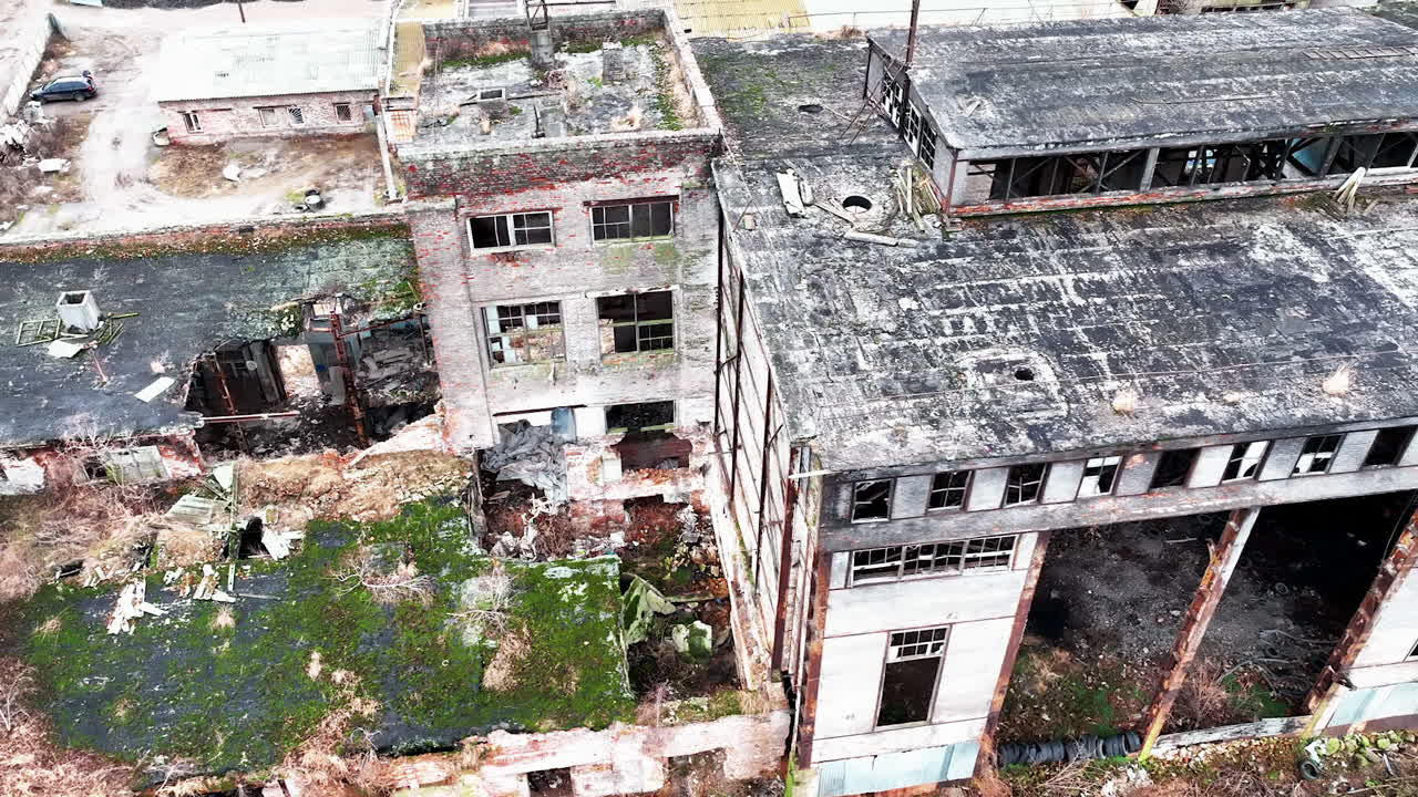Debris and construction garbage inside and outside the broken factory buildings. Ruined plant exterior from aerial perspective.