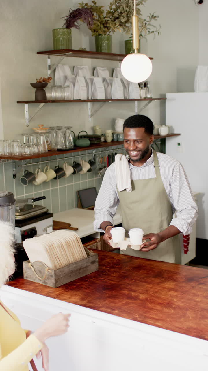 Vertical video: Barista in apron serving coffee to customer in cozy cafe setting