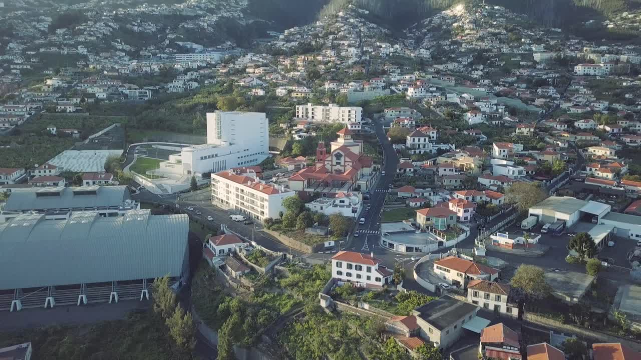 Community Church in overpopulated Santo Antonio city in Madeira aerial reverse track shot