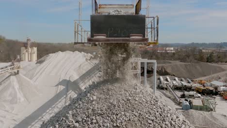 static slow motion footage of gravel rocks being dropped off a conveyor belt and falling into a large pile.