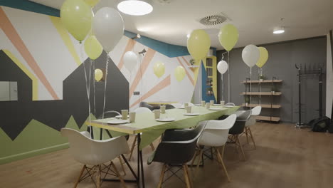 a party room decorated with balloons and a long table set for an event