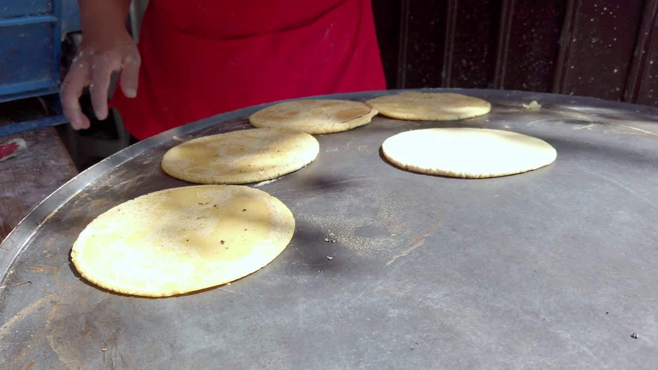 Hand cooking tortillas on stovetop, traditional food, sunny atmosphere