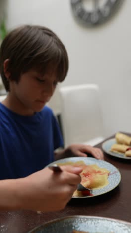 child eating crepes with strawberry jam