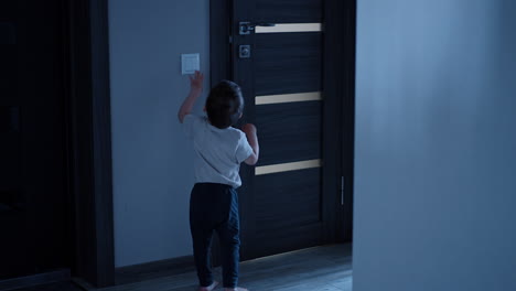 toddler runs up to the light switch, turns it on and enters the bathroom. kid takes a prop, stands on it and opens water.