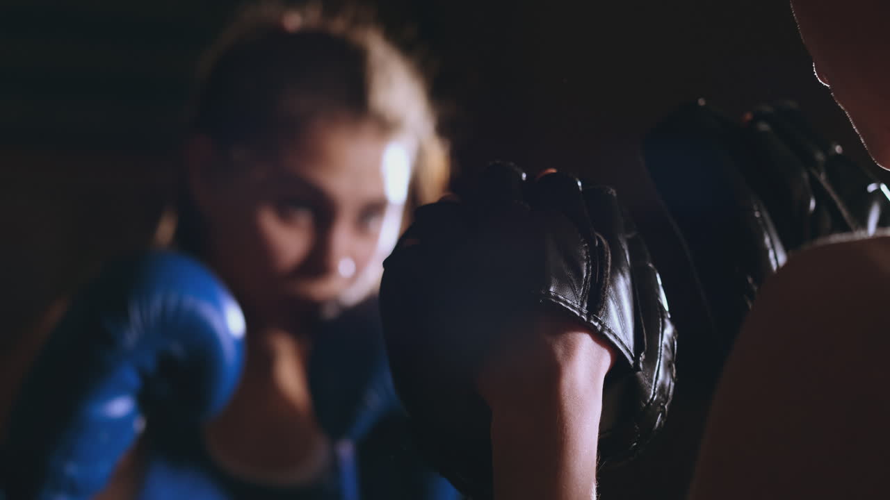 mujer adulta joven haciendo entrenamiento de kickboxing con su entrenador.