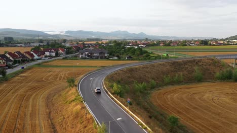 Silbernes-Auto,-Das-Im-Sonnenuntergang-Die-Brücke-In-Gelber-Ländlicher-Landschaft-Ansteuert