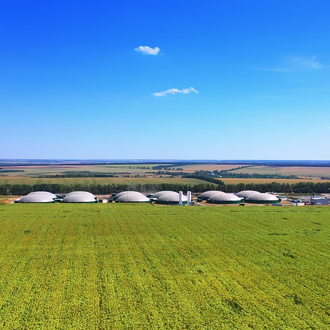 Modern bio fuel factory locating in the picturesque farmlands. Sunny summer day nature. Blue sky at backdrop. Top view