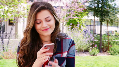 female high school student checking messages on mobile phone outside college buildings