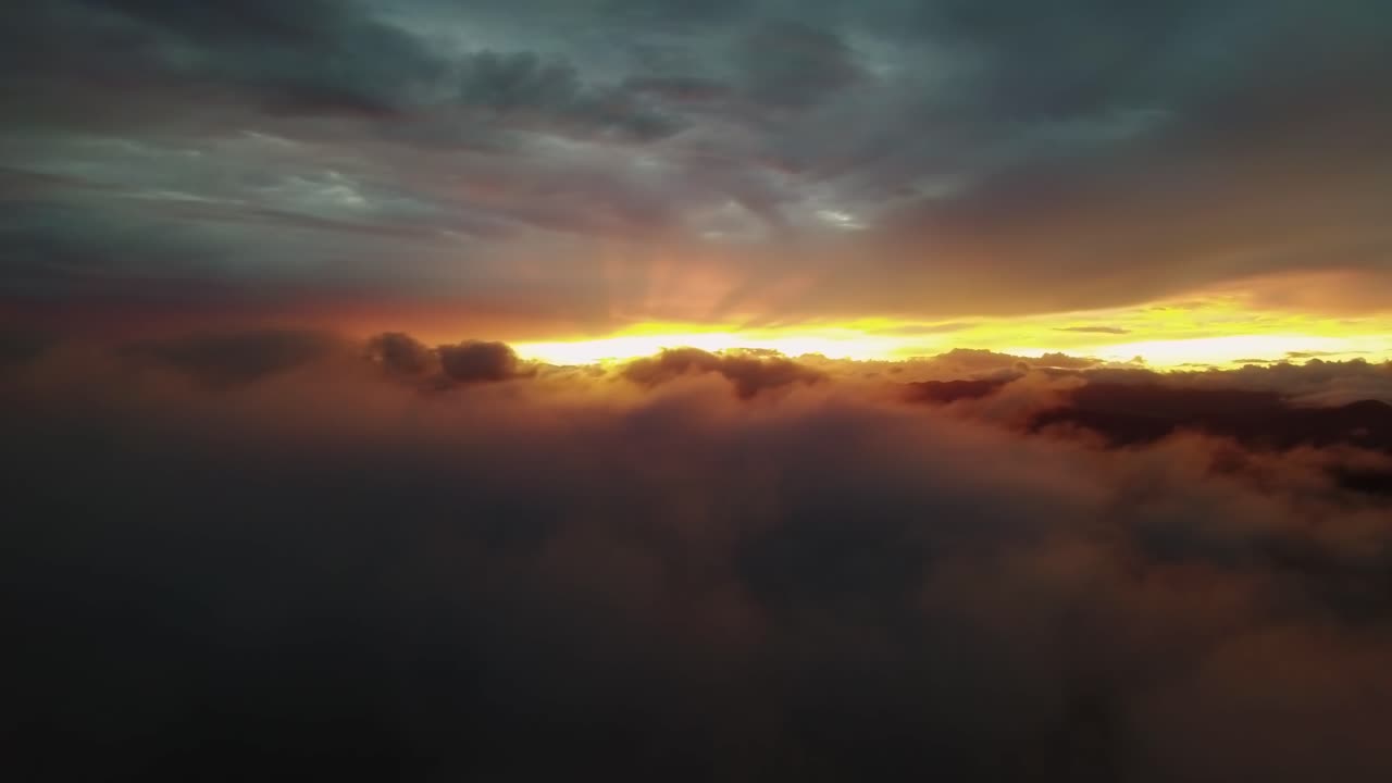 paisaje natural artístico, rayos de sol anaranjados brillando a través de nubes oscuras al atardecer, dron 4k