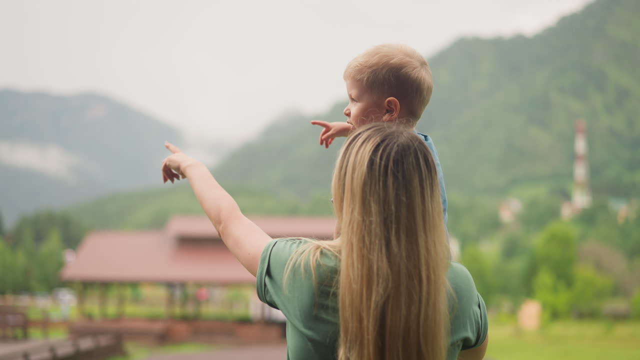 엄마와 어린 소년은 산의 전망을 가진 계곡을 즐기고 있습니다.
