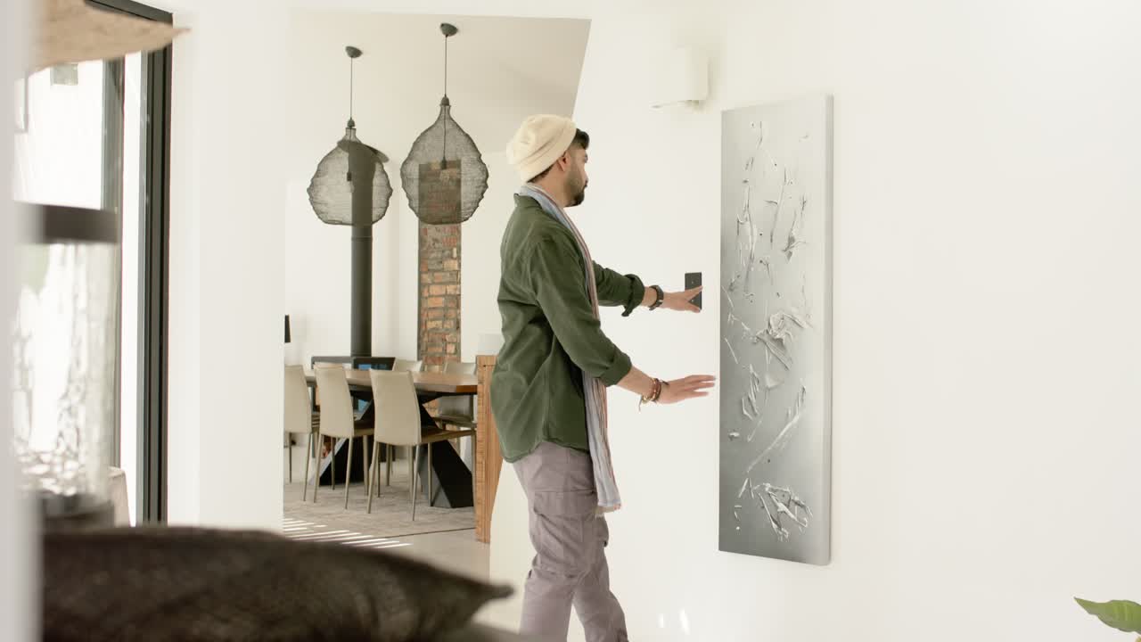 Holding panel, Indian man placing panel on white wall at home, sliding, surveying alignment