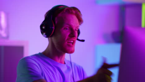 excited man celebrating cyber tournament success closeup. happy gamer in neon