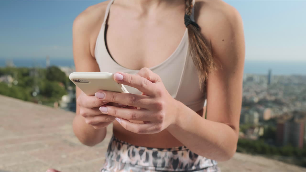 mujer deportista usando un teléfono inteligente después de un entrenamiento al aire libre. manos de mujer escribiendo en el teléfono