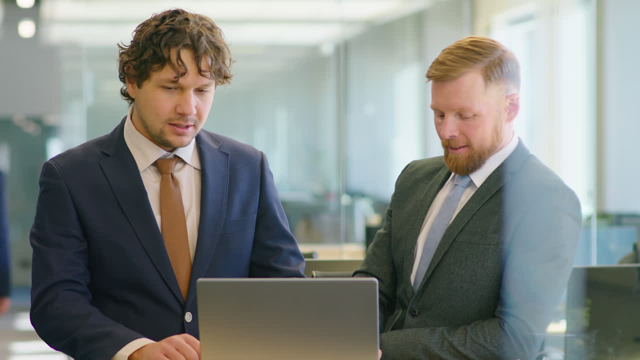 Colleagues Using Laptop and Talking in Office