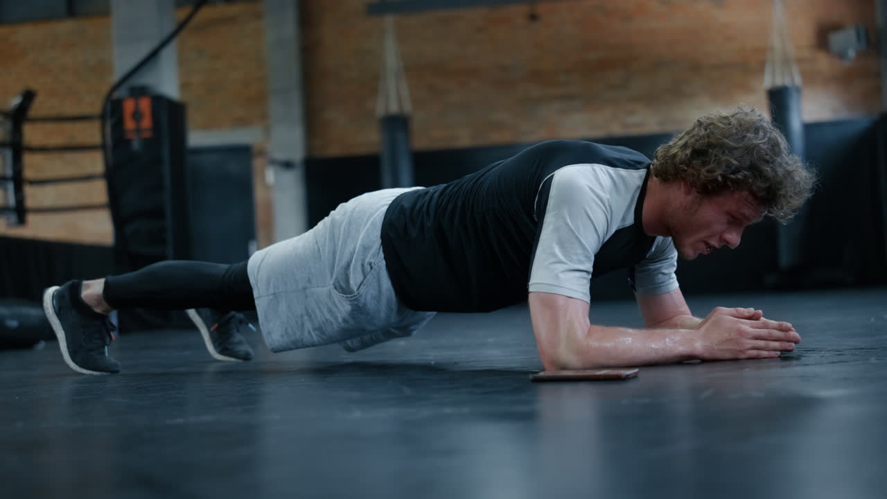 체육관 에서 피곤 한 전투기 훈련.  ⁇ 박서 가 플랜크 피트니스 센터 에 서 있는 것