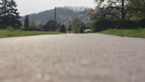 Man-walking-in-distance-on-road-towards-camera-at-sunset