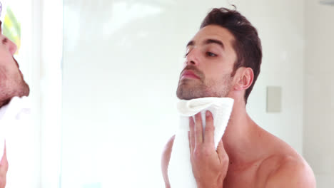 man wiping his face in front of mirror