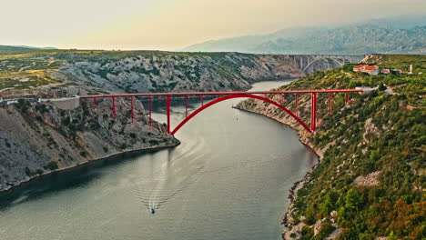 wide aerial shot of a big red bridge on a beautiful mountain scenery on sunset, camera moving sideways