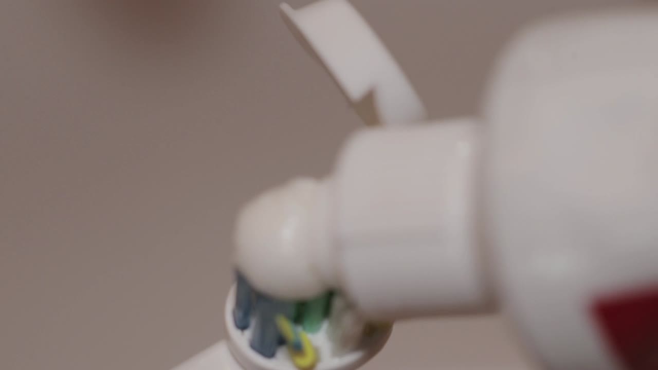 Detail shot of toothpaste put on an electric toothbrush