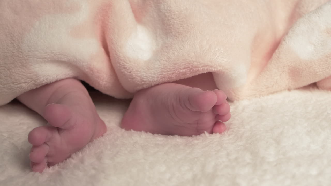 Beautiful Baby newborn is lying in bed and shows hands and feet, mother fandles with baby and covers her up with a cosy coverlet,4k 60p Apple ProRes422, with external Atoms recorder-9