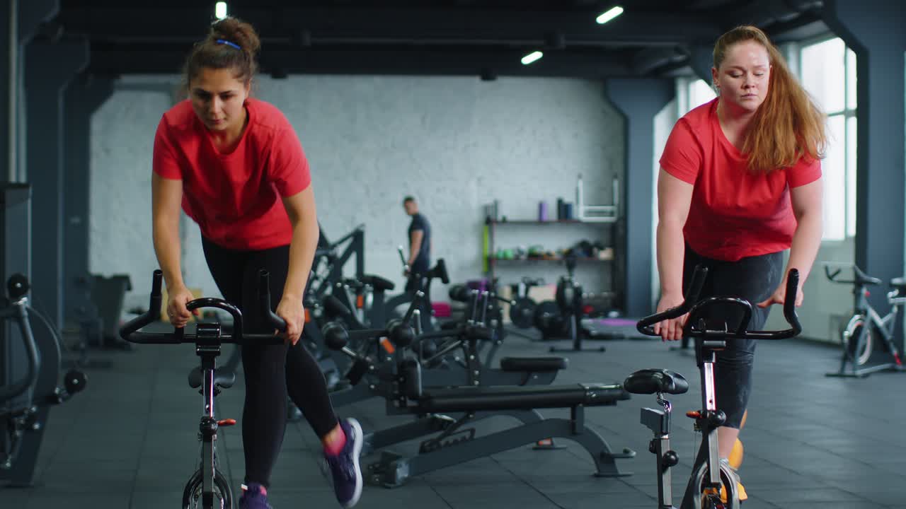 Athletic women group riding on spinning stationary bike training routine in gym weight loss indoors