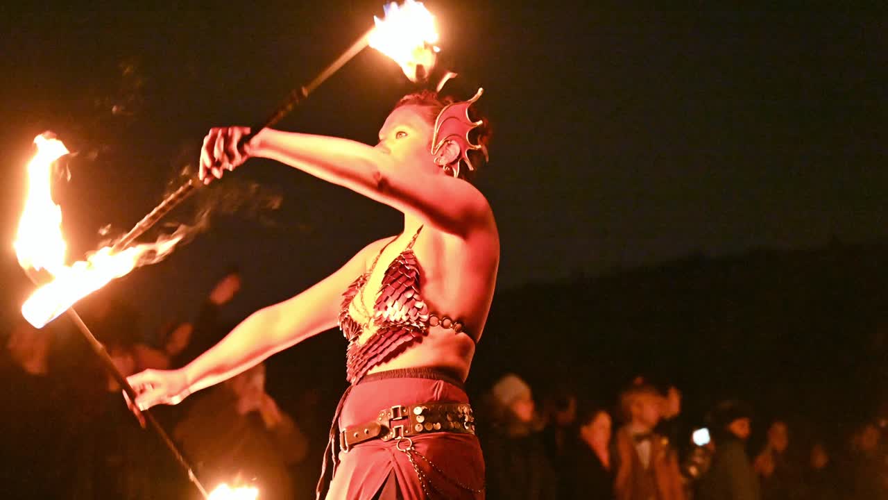 Woman in a mermaid costume twirls fire batons, Edinburgh Samhain festival