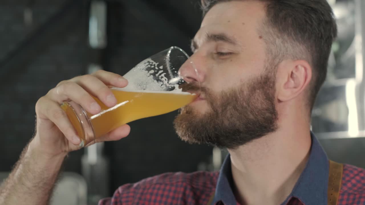 un joven cervecero con un delantal de cuero está probando cerveza en una cervecería moderna