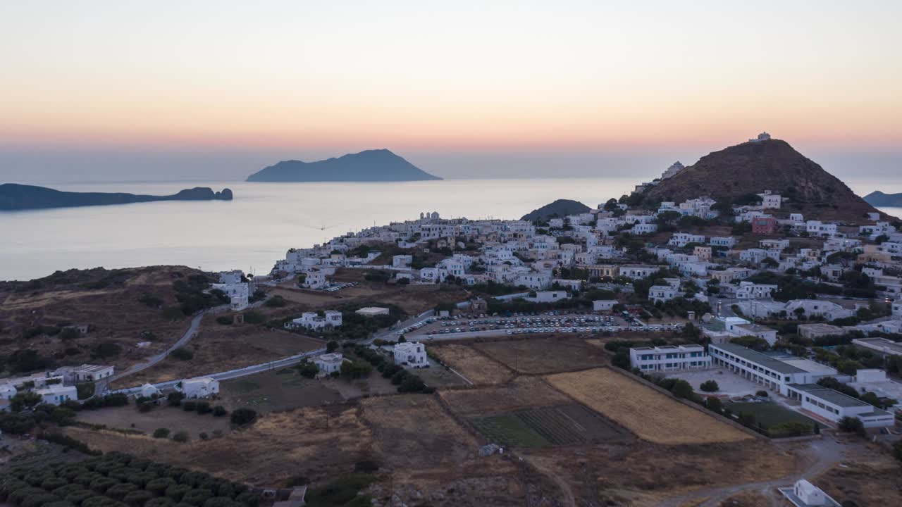 hiperlapso aéreo sobre un típico pueblo griego al atardecer con vistas al mar egeo, cícladas, grecia