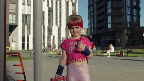 caucasian girl in sportswear making exercises with dumbbells. workout for kids. athletic child