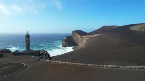 Backward-aerial-reveals-lighthouse-on-Capelinhos-Volcano,-last-erupted-in-1957