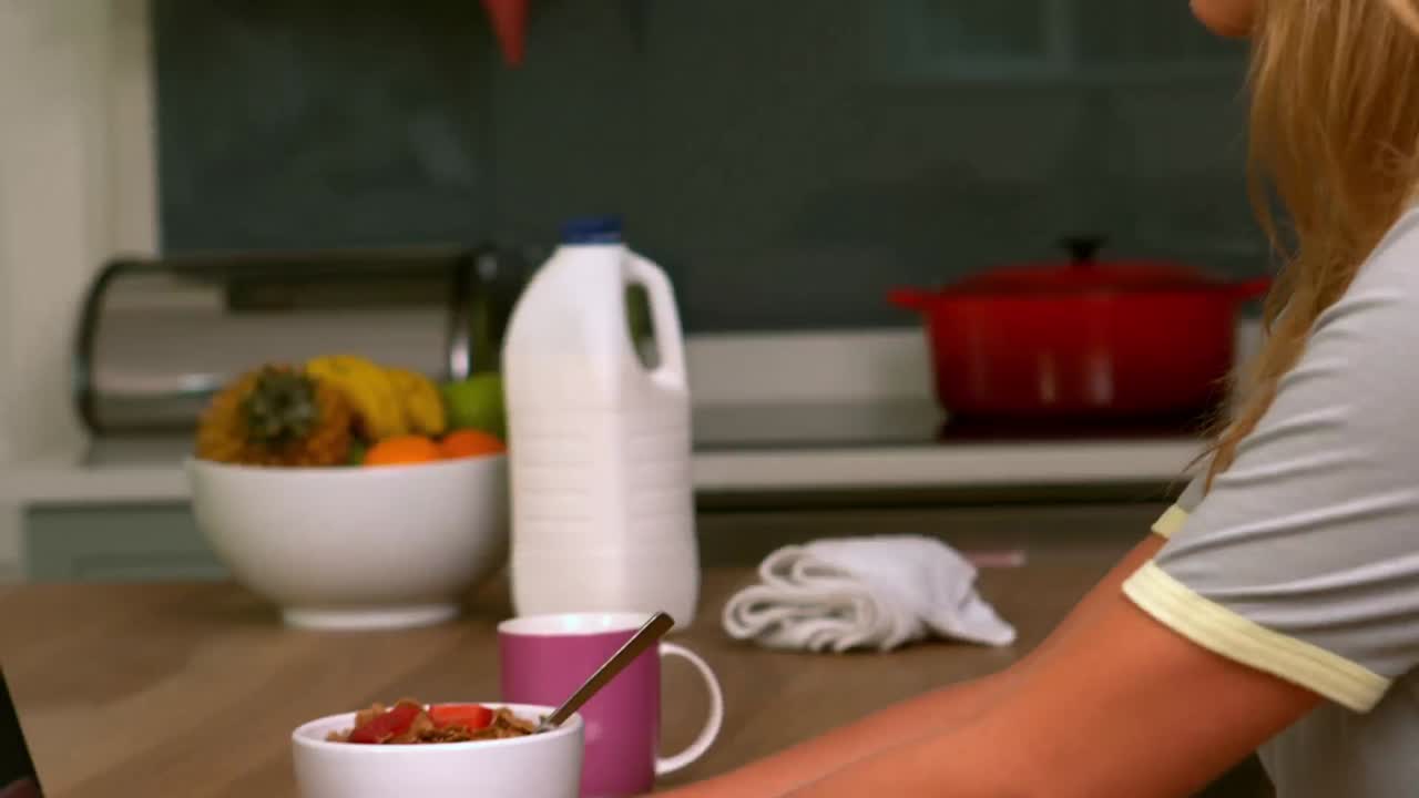 mujer bonita usando computadora portátil en la cocina