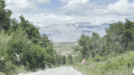 driving on the road towards the mountain range with snowcap peaks