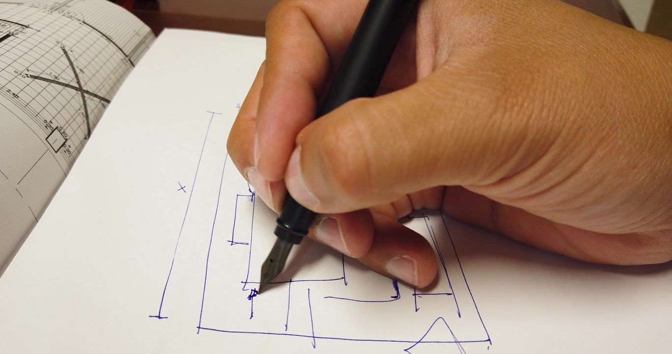 Inquadratura statica di un architetto che disegna figure geometriche con una penna stilografica su un foglio di carta
