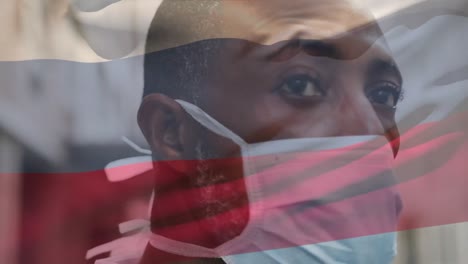 Animation-Der-Flagge-Von-Coumbia,-Die-über-Einem-Afroamerikanischen-Mann-Mit-Gesichtsmaske-In-Der-Stadtstraße-Weht