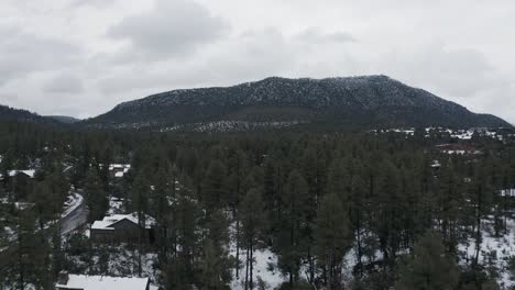 Tiro-Aéreo-Ascendente-A-Través-De-árboles-Y-Terreno-Cubierto-De-Nieve-Para-Revelar-Una-Montaña-En-El-Norte-De-Arizona