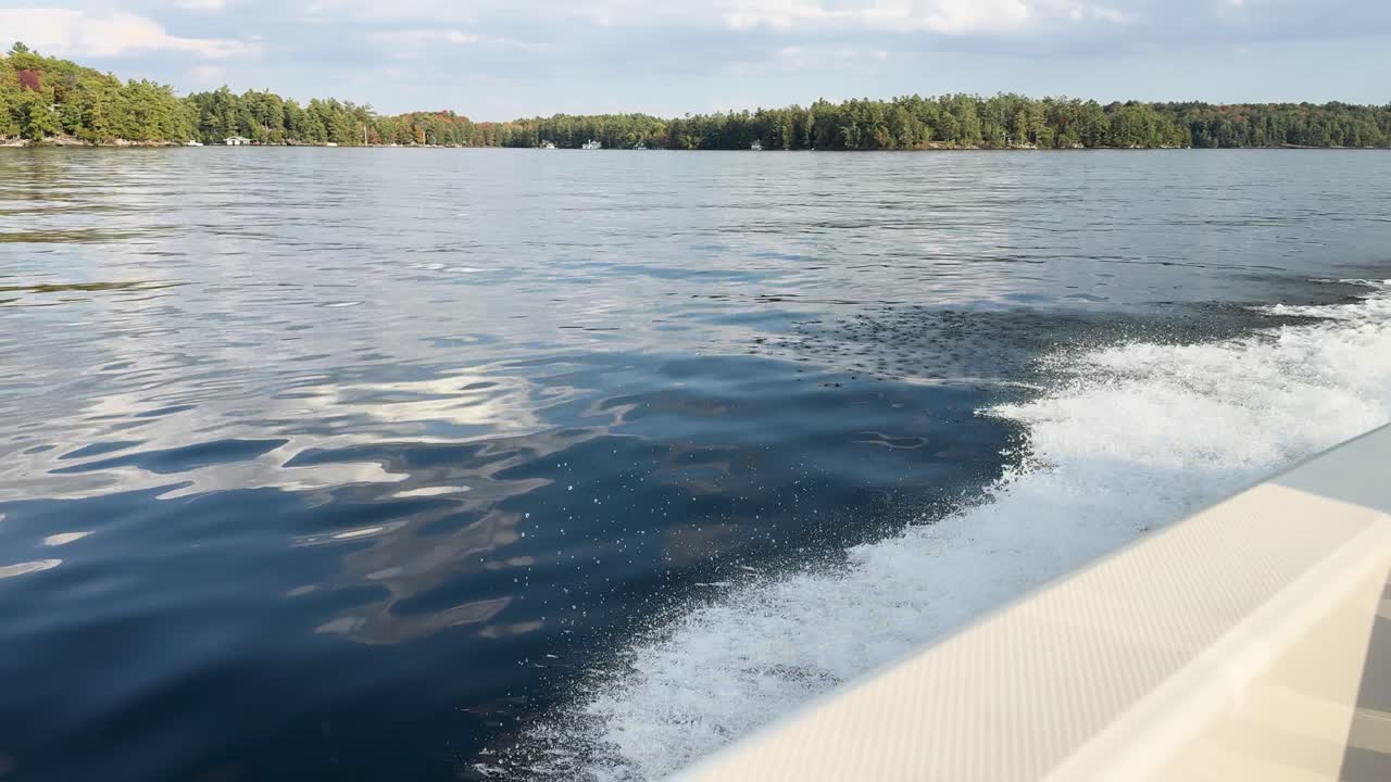 Onboard shot capturing motorboat sailing across Muskoka Lake, Ontario, with blue waters and scenic forest horizon