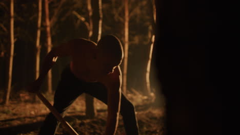 man chopping wood in the forest at night