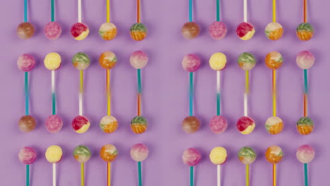 sweet lollipops on color purple background. bright texture sugar candies close up top view. composition of favorite children's summer sweets. studio shot for shop, supermarket, confectionery