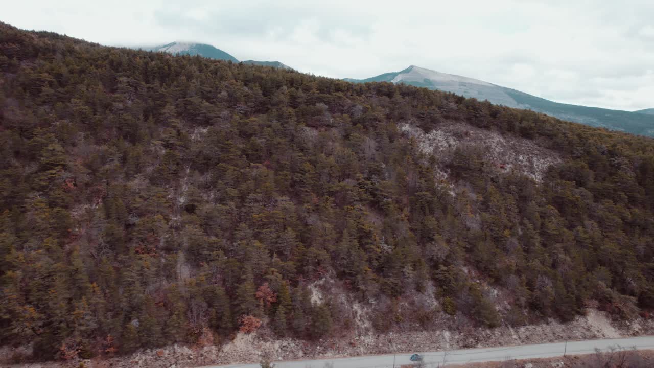 Aerial View of a Car Driving on a Mountain Road through a Forest
